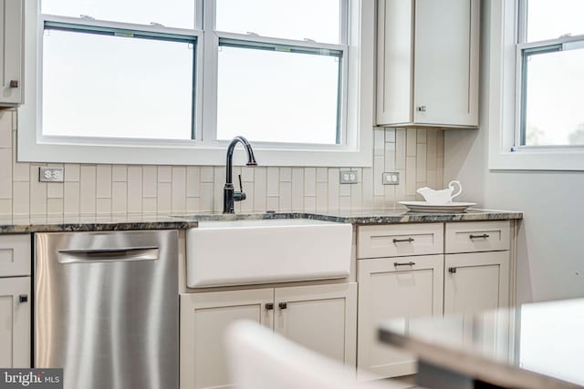 kitchen with dark stone countertops, dishwasher, decorative backsplash, and a sink