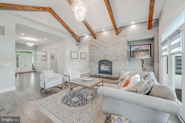 living area with a chandelier, high vaulted ceiling, beamed ceiling, and a fireplace