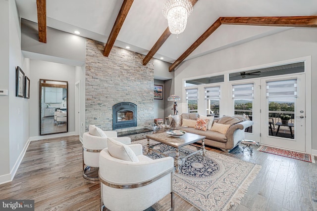 living area featuring high vaulted ceiling, beamed ceiling, a healthy amount of sunlight, and a stone fireplace