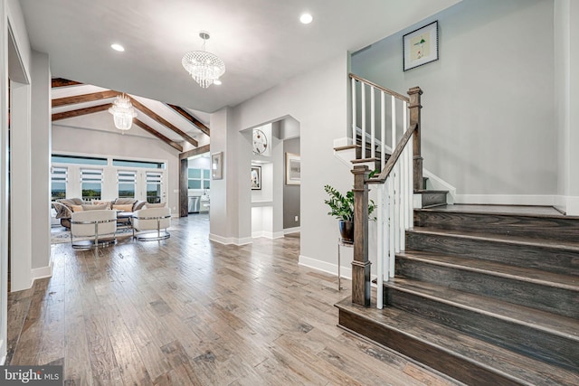 entryway with vaulted ceiling with beams, a notable chandelier, stairs, and wood finished floors