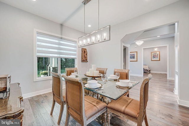 dining space with light wood-type flooring, recessed lighting, arched walkways, and baseboards