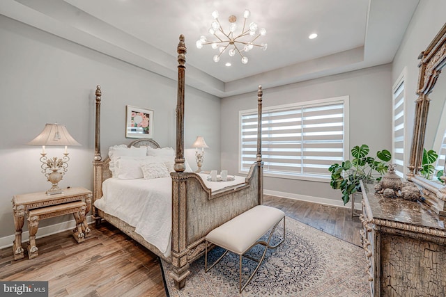 bedroom featuring wood finished floors, a chandelier, baseboards, and multiple windows