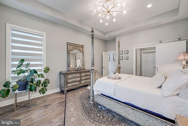 bedroom featuring recessed lighting, a notable chandelier, a raised ceiling, baseboards, and wood finished floors