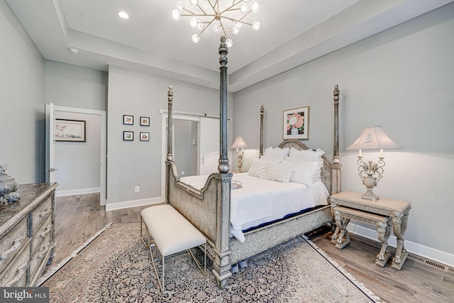 bedroom featuring a tray ceiling, wood finished floors, and baseboards