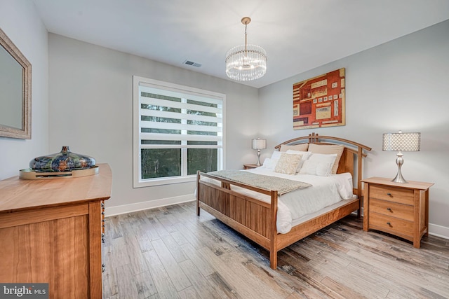 bedroom featuring baseboards, a notable chandelier, and light wood-style flooring