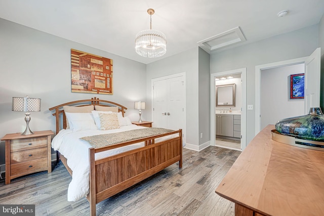 bedroom with connected bathroom, light wood-style flooring, attic access, a sink, and baseboards