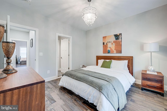 bedroom featuring baseboards, wood finished floors, and an inviting chandelier