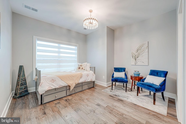 bedroom featuring an inviting chandelier, wood finished floors, visible vents, and baseboards