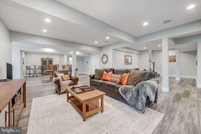 living room featuring baseboards, light wood-type flooring, stairs, and recessed lighting