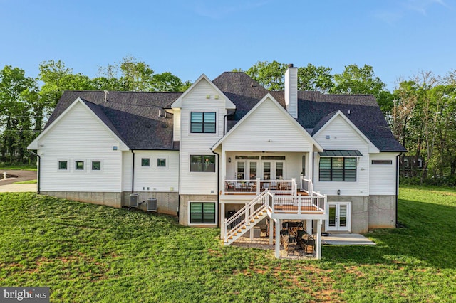 back of property featuring a chimney, stairway, a wooden deck, french doors, and a lawn