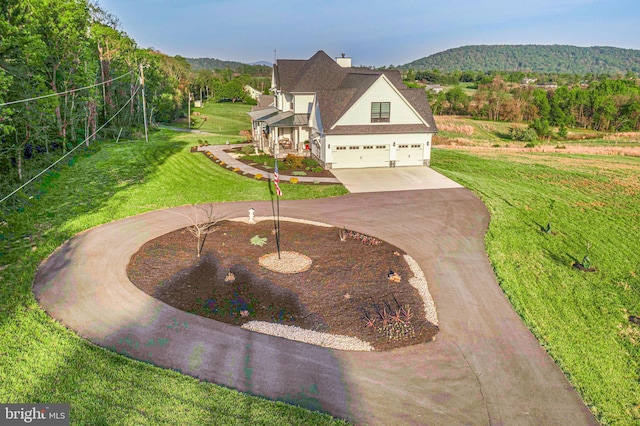 view of front of home featuring a mountain view, curved driveway, and a front yard