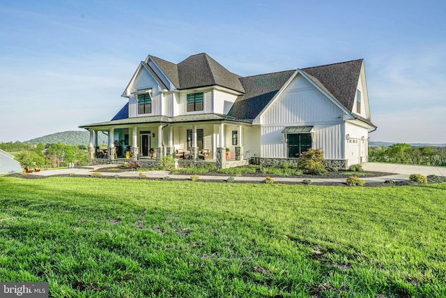 view of front of house featuring a porch, board and batten siding, driveway, stone siding, and a front lawn