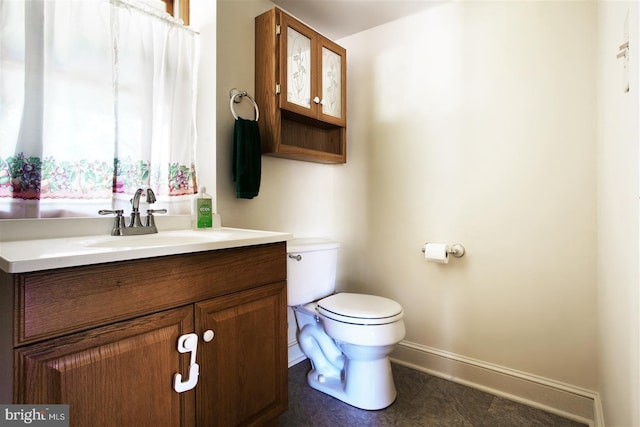 bathroom featuring toilet, vanity, and baseboards