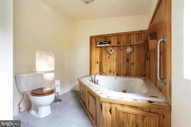 bathroom featuring toilet, baseboards, and a tub with jets