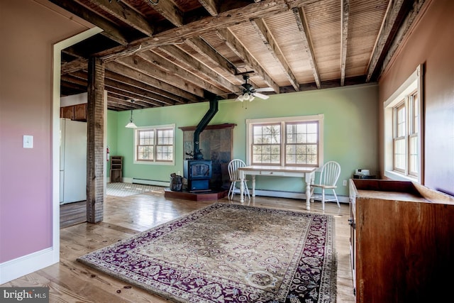 interior space with a baseboard heating unit, baseboards, baseboard heating, a ceiling fan, and a wood stove