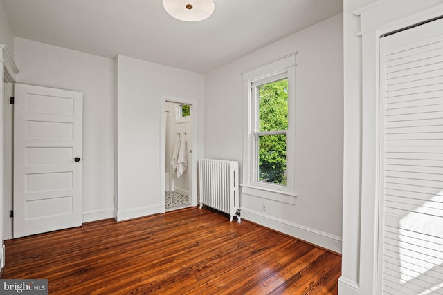 unfurnished bedroom featuring radiator heating unit, baseboards, and dark wood-style flooring
