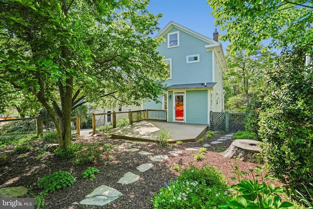 back of house with fence, a chimney, a patio area, and a deck