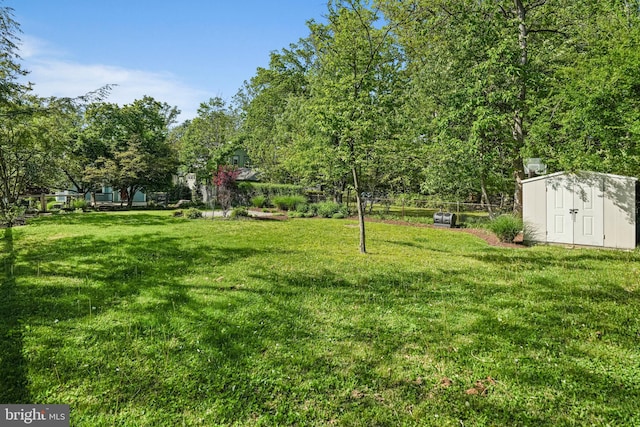 view of yard with fence, an outbuilding, and a shed