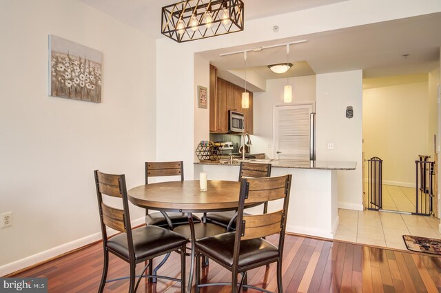 dining area with hardwood / wood-style flooring, baseboards, and track lighting