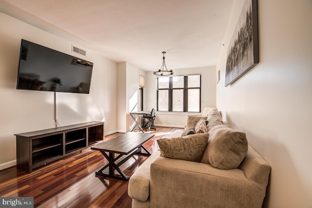 living area with a chandelier, hardwood / wood-style floors, visible vents, and baseboards
