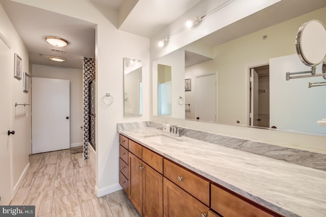 bathroom with marble finish floor, visible vents, vanity, baseboards, and walk in shower