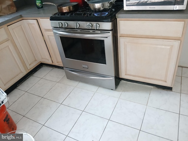 kitchen with stainless steel appliances, dark countertops, and light tile patterned flooring