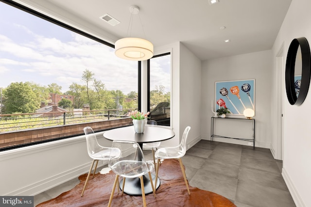 dining space featuring baseboards, concrete floors, and visible vents