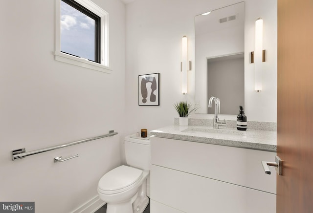 half bathroom featuring vanity, toilet, and visible vents