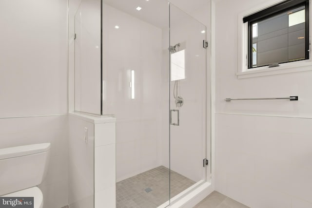 full bathroom with a wainscoted wall, a shower stall, toilet, and tile walls