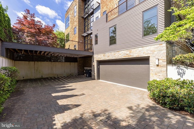 view of side of home with a garage, decorative driveway, and stone siding