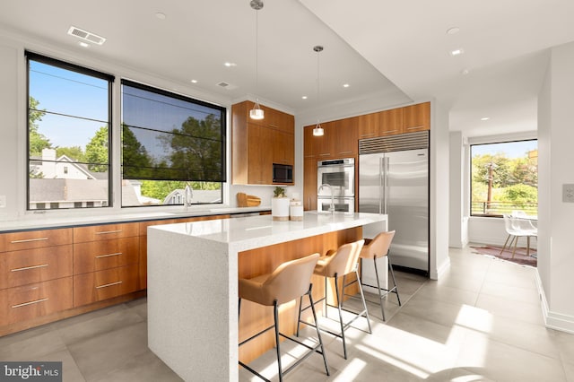 kitchen with brown cabinetry, visible vents, modern cabinets, a sink, and built in appliances