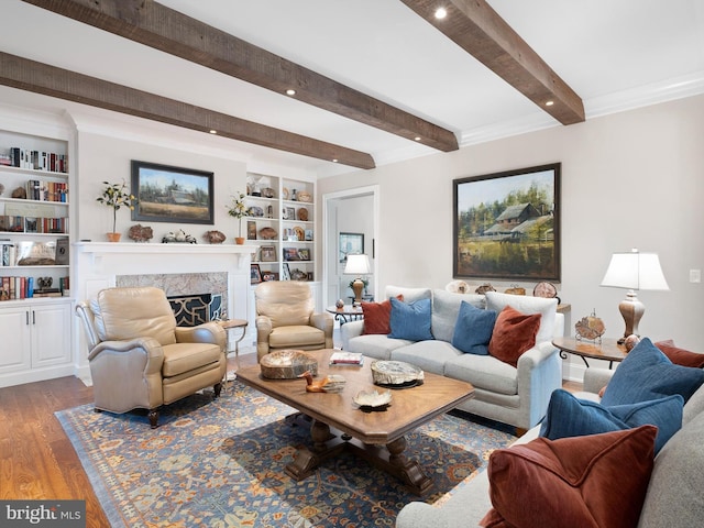 living room with a fireplace, built in shelves, recessed lighting, wood finished floors, and beamed ceiling