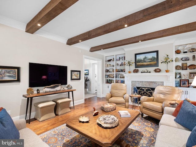 living room with built in shelves, baseboards, beam ceiling, and wood finished floors