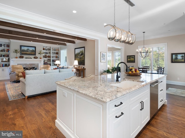 kitchen with dark wood-style flooring, an inviting chandelier, light stone counters, a sink, and white cabinetry