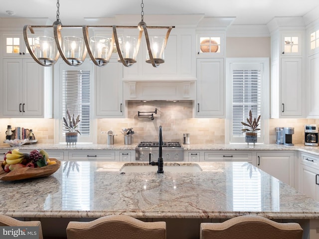 kitchen featuring glass insert cabinets, white cabinets, backsplash, and a notable chandelier