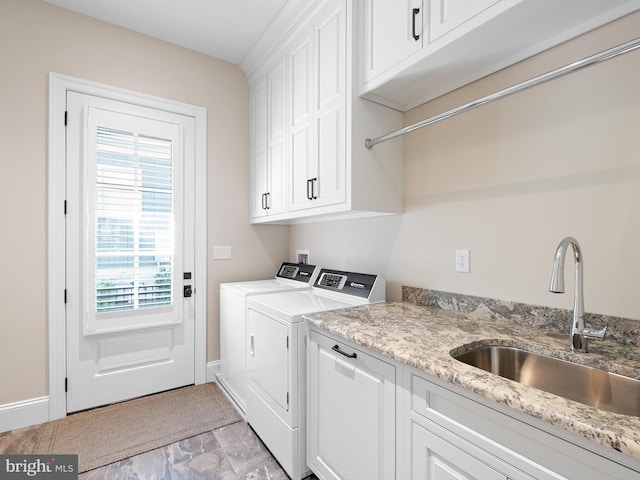 clothes washing area with plenty of natural light, a sink, cabinet space, and washer and clothes dryer