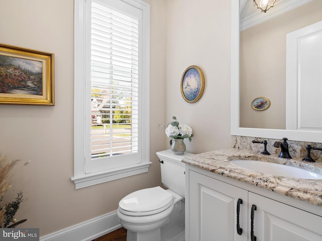 bathroom featuring toilet, ornamental molding, and vanity