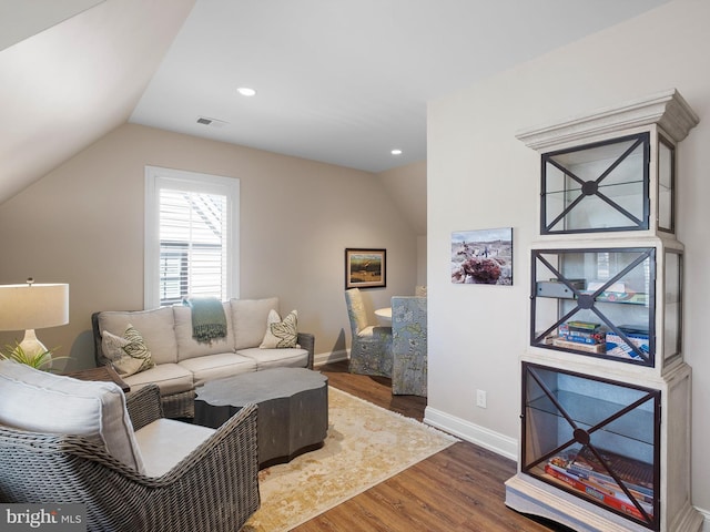 living room featuring baseboards, lofted ceiling, wood finished floors, and visible vents