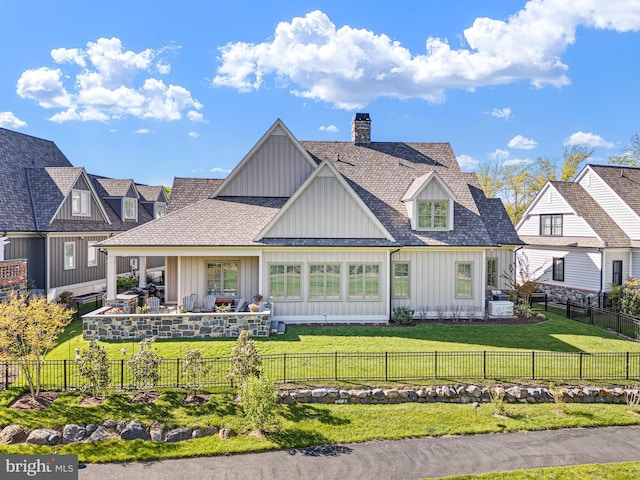 back of house with a lawn, a fenced backyard, board and batten siding, and a chimney