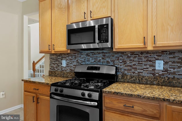 kitchen featuring light stone counters, baseboards, appliances with stainless steel finishes, and backsplash