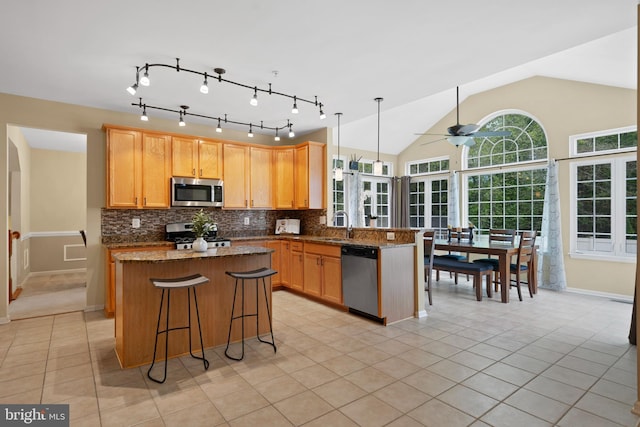 kitchen featuring ceiling fan, stainless steel appliances, light tile patterned floors, tasteful backsplash, and a kitchen island