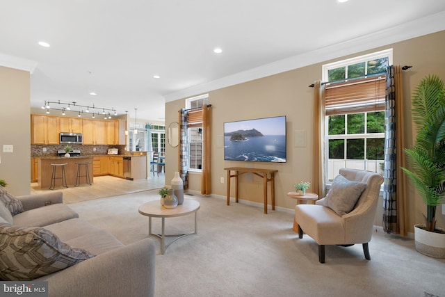 living room featuring plenty of natural light, baseboards, ornamental molding, and light colored carpet