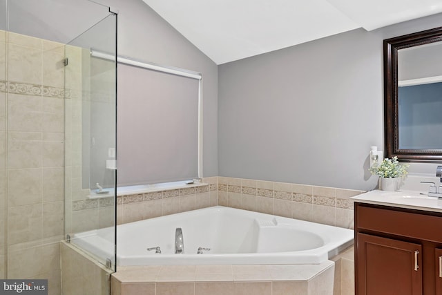 bathroom with vaulted ceiling, a shower stall, a bath, and vanity