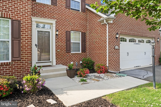 doorway to property with a garage and brick siding