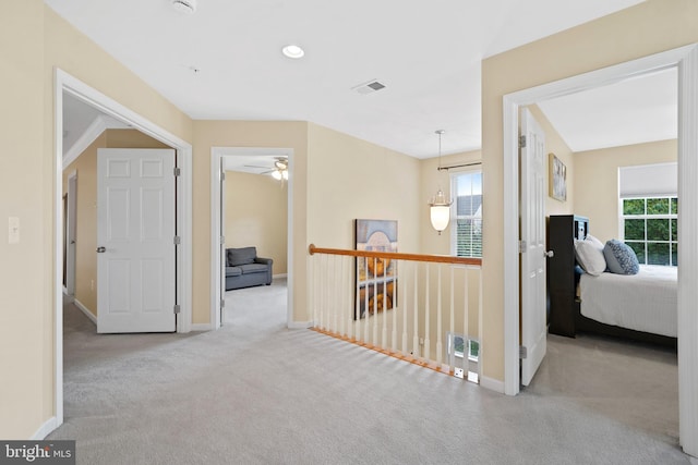 hall with carpet floors, baseboards, and visible vents