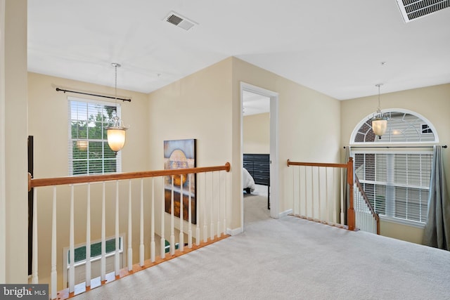 corridor with carpet flooring, baseboards, an upstairs landing, and visible vents