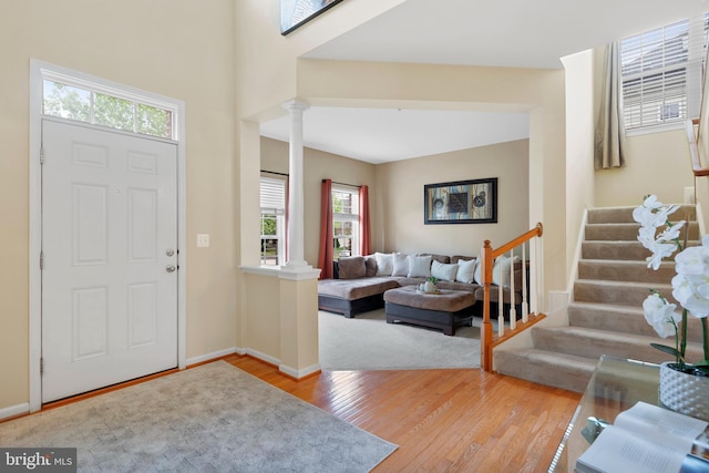 entrance foyer with wood-type flooring, decorative columns, baseboards, and stairway