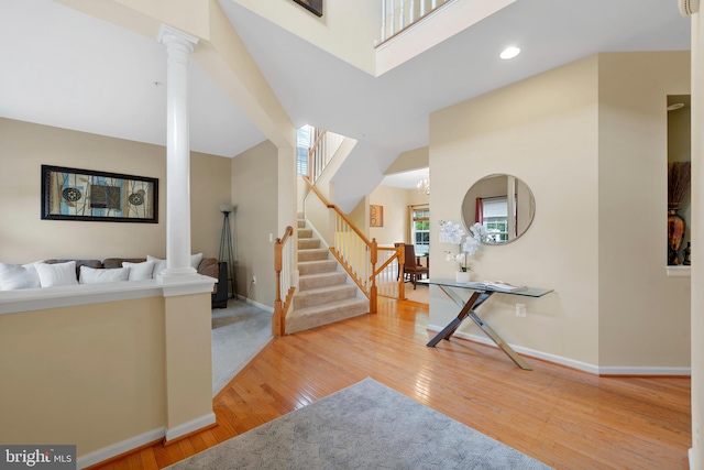 entryway with ornate columns, baseboards, wood finished floors, and stairway
