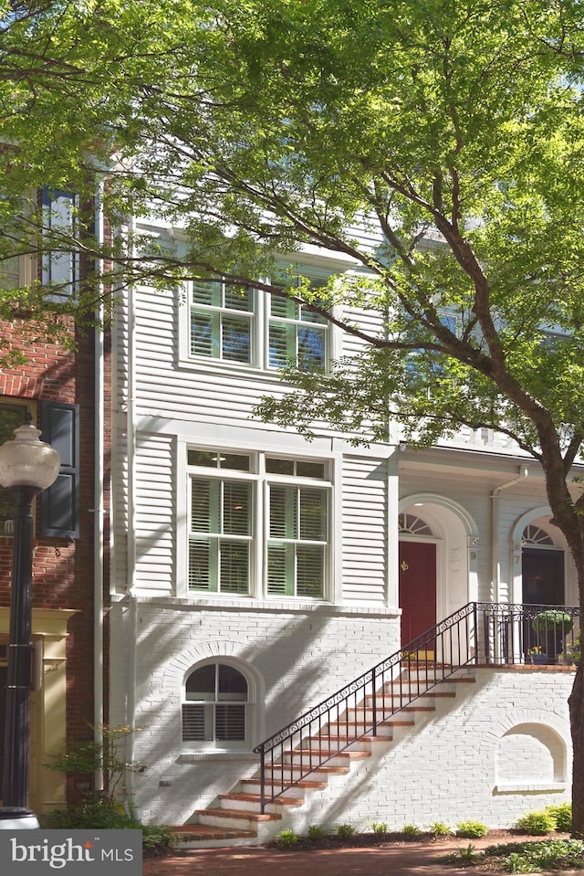 view of front of house featuring stairs and brick siding