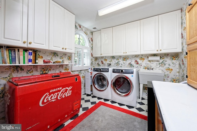 clothes washing area featuring wallpapered walls, cabinet space, tile patterned floors, and washing machine and clothes dryer